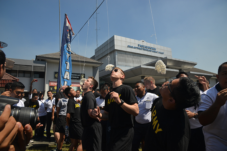 Lomba makan kerupuk antara mahsiswa STTAL dan kadet US Army di Lapangan Apel Bumimoro STTAL, Surabaya, Selasa (25/7).